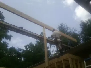 Carpenter setting a ridge beam over a new addition frame — Ice Dam Removal by Roofing Brothers in Smithville